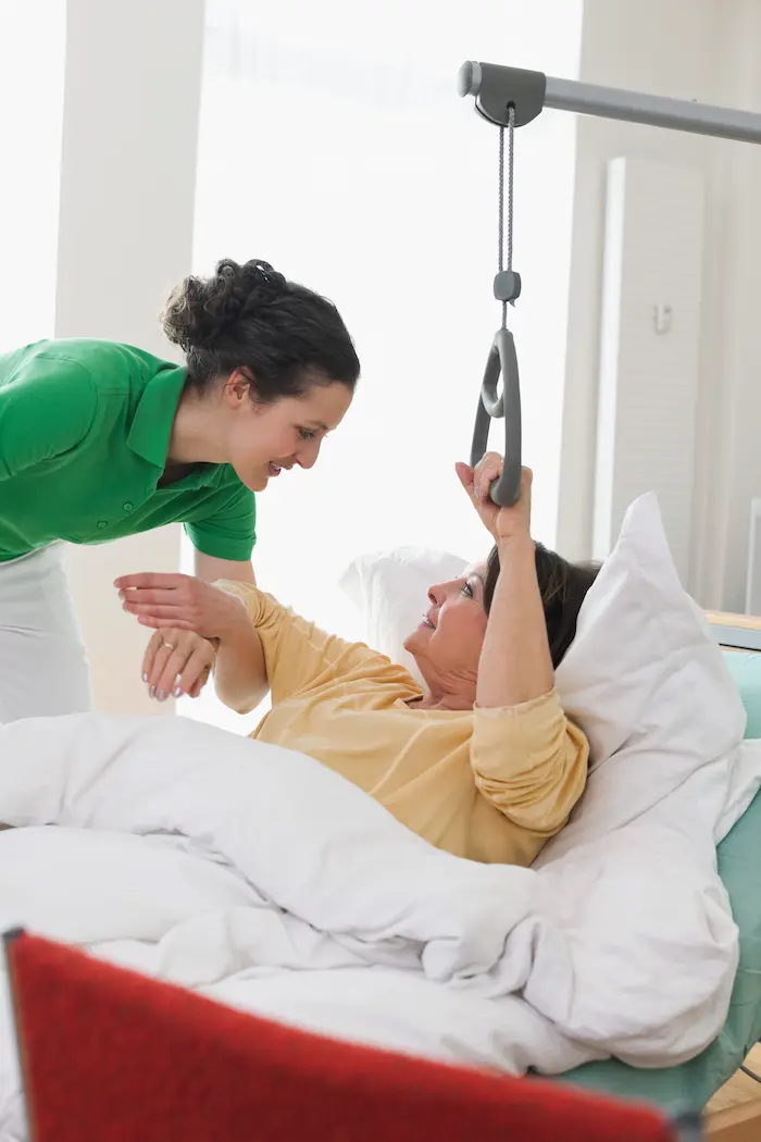 Eine Frau liegt in einem Pflegegbett und spricht mit ihrer Pflegerin