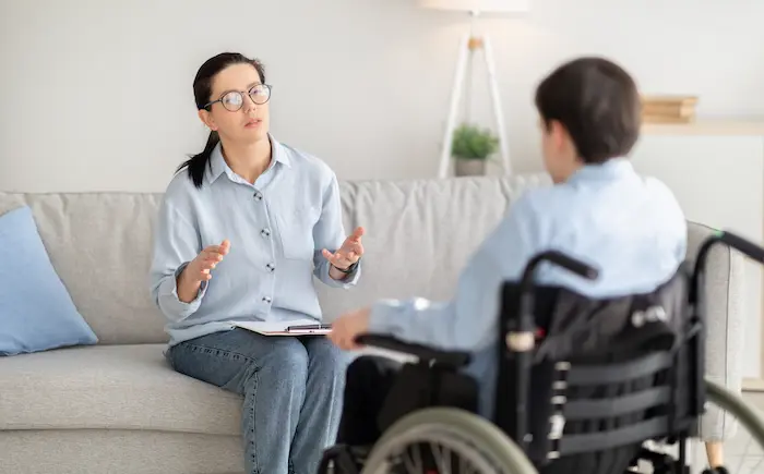 Ein Mann im Rollstuhl wird von einer Pflegeberaterin zu Hilfsmitteln beraten